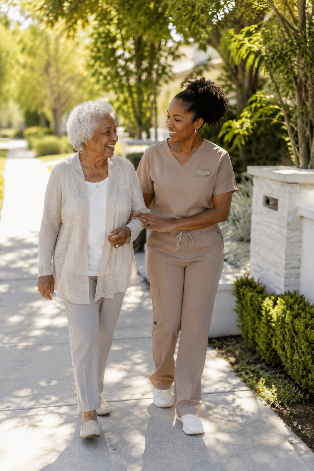 A caregiver and senior woman walking arm in arm outdoors on a sunny day